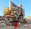 Hjelpemannskap nærmar seg ein skadd bygning etter kraftige regnbyger og storm i byen Derna i Libya.