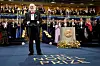 Nobelprisvinnaren i litteratur, Jon Fosse, etter å ha teke imot prisen frå kong Carl Gustaf i Konserthuset i Stockholm søndag. Anders Olsson, som heldt presentasjonstalen, står bak talarstolen.
