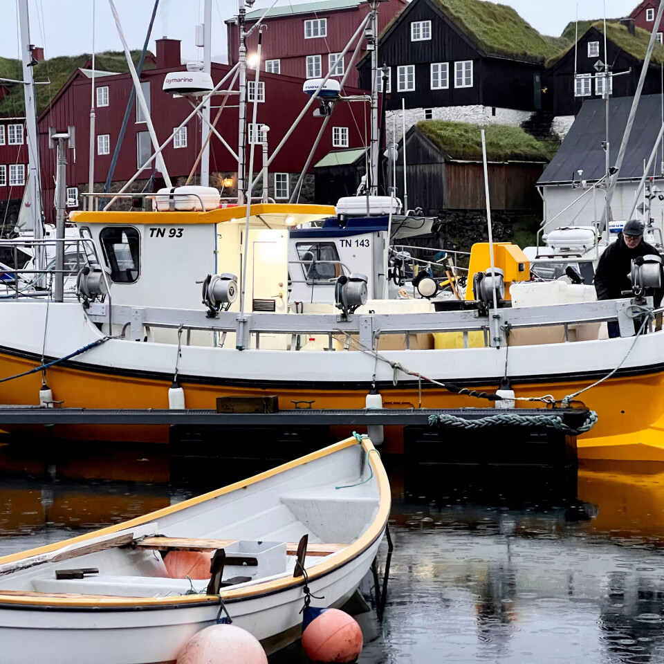 Det er duskregn og mørkt. Ein kar med kaps og briller står om bord i ein sjark, og bakom han ligg Tinganes. Det er duskregn og mørkt. Ein kar med kaps og briller står om bord i ein sjark, og bakom han ligg Tinganes.