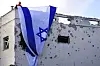 Municipality workers hang an Israeli flag over a damaged building that was hit by a rocket fired from Lebanon, in Kiryat Bialik, northern Israel, on Sunday, Sept. 22, 2024. (AP Photo//Ariel Schalit)
