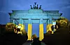 Passersby photograph the Brandenburg Gate in Berlin, illuminated in the Ukrainian national colors, before a commemorative event marking the third anniversary of the Russian attack on Ukraine, Monday Feb. 24, 2025. (Sebastian Christoph Gollnow/dpa via AP)